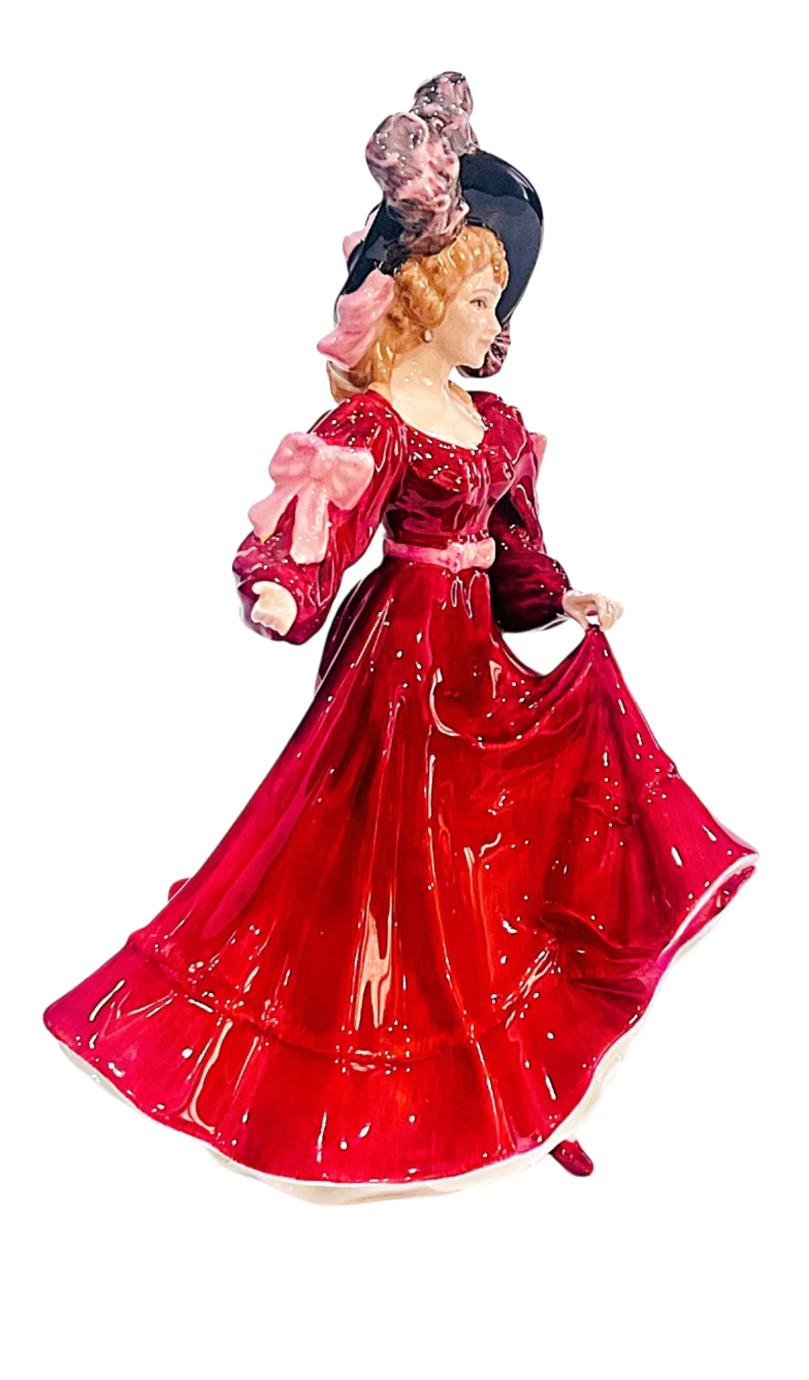 Figurine of a woman in a red dress with a black hat on a white background