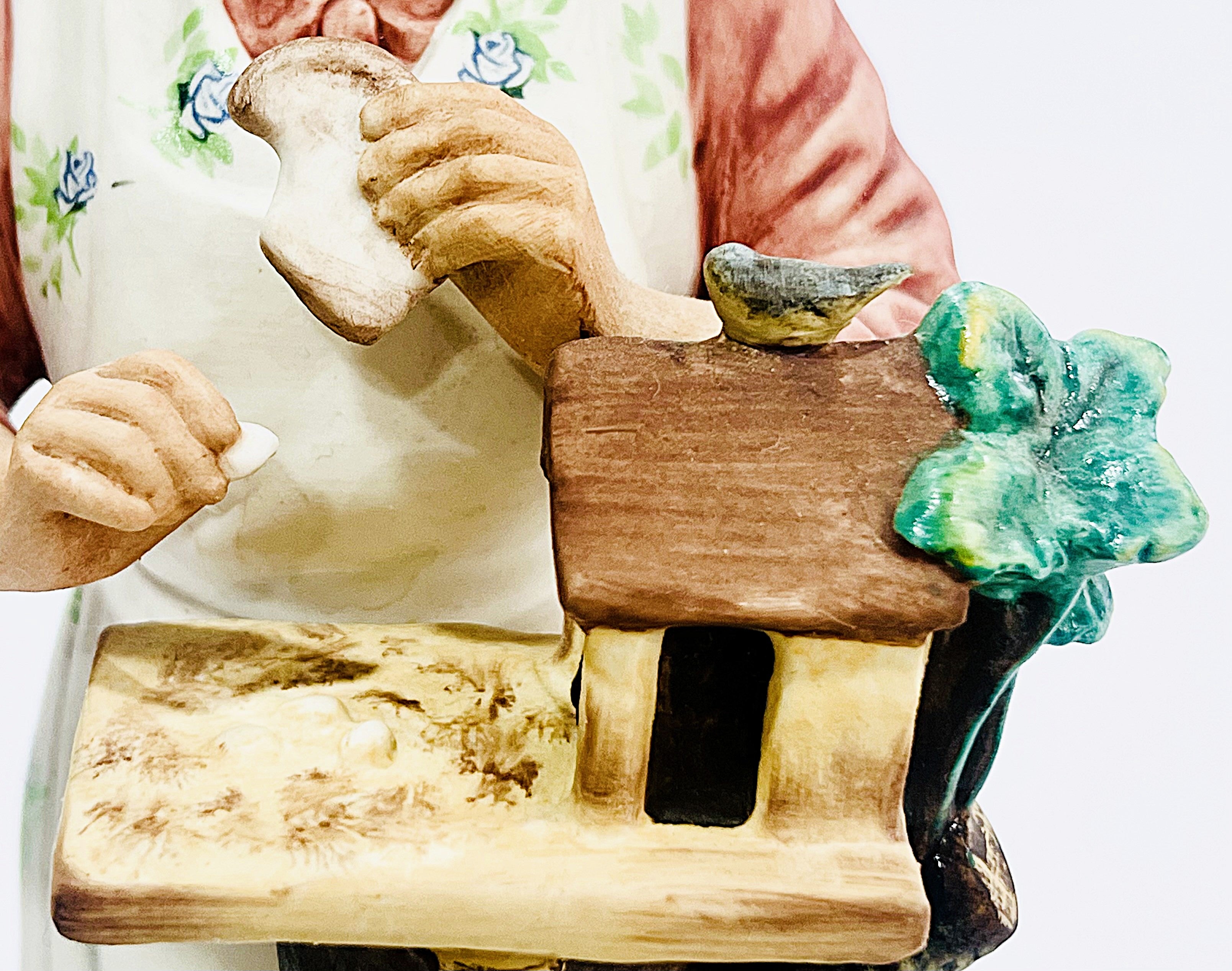 Person holding a bread feeding a bird with a green handle, possibly used for gardening or farming.