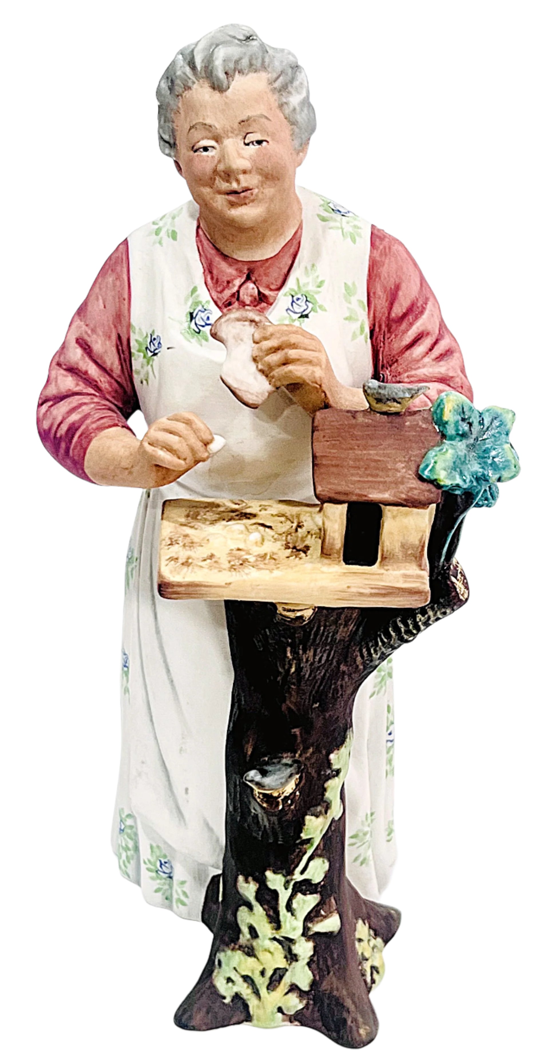 Decorative figurine of an elderly woman with a birdhouse on a white background