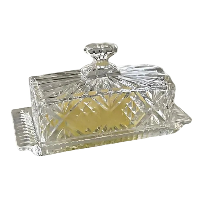 A crystal butter dish with a cover, featuring a geometric pattern and a lid with a handle.