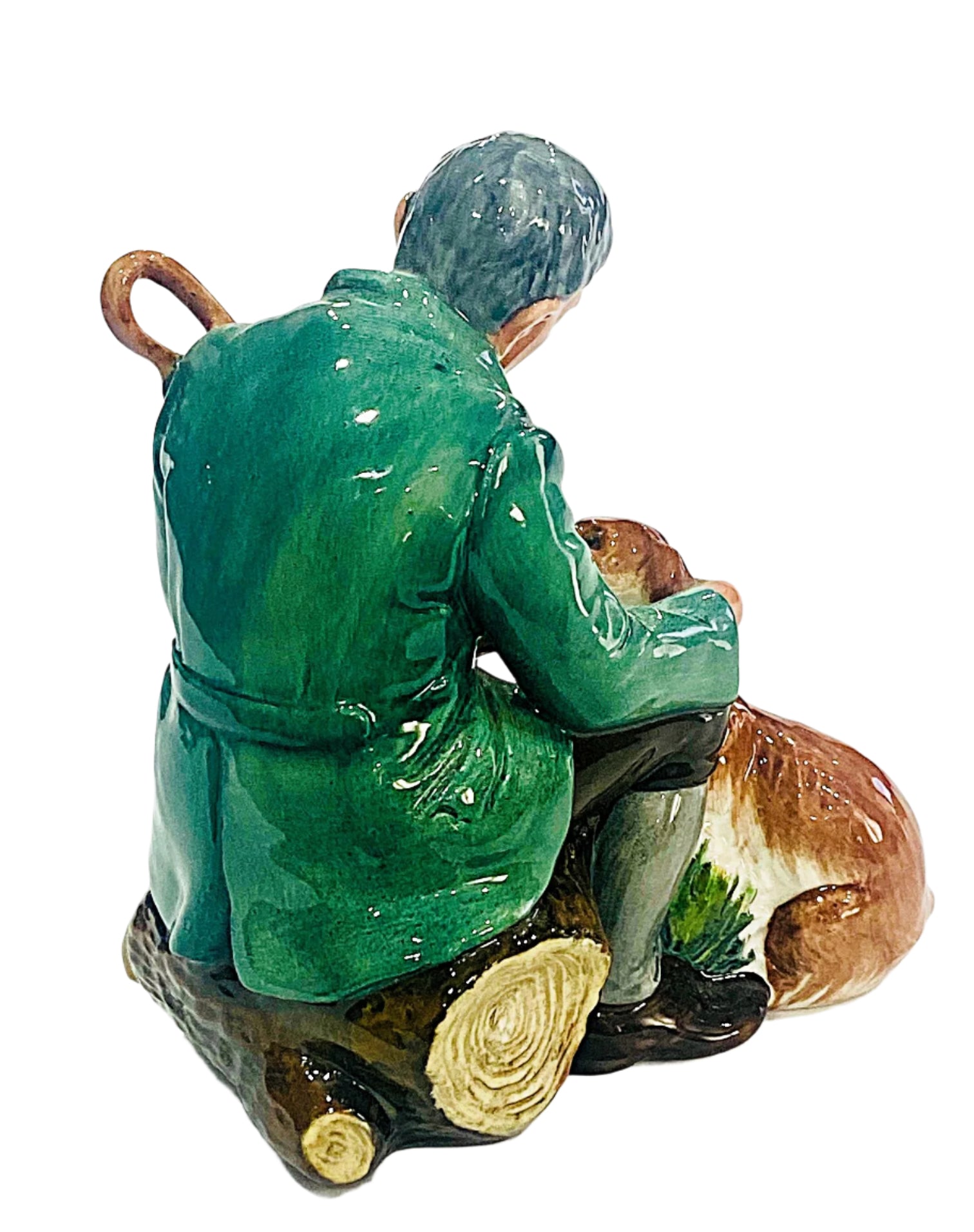 Figurine of a person in green clothing sitting on a log with a dog next to them, on a white background.