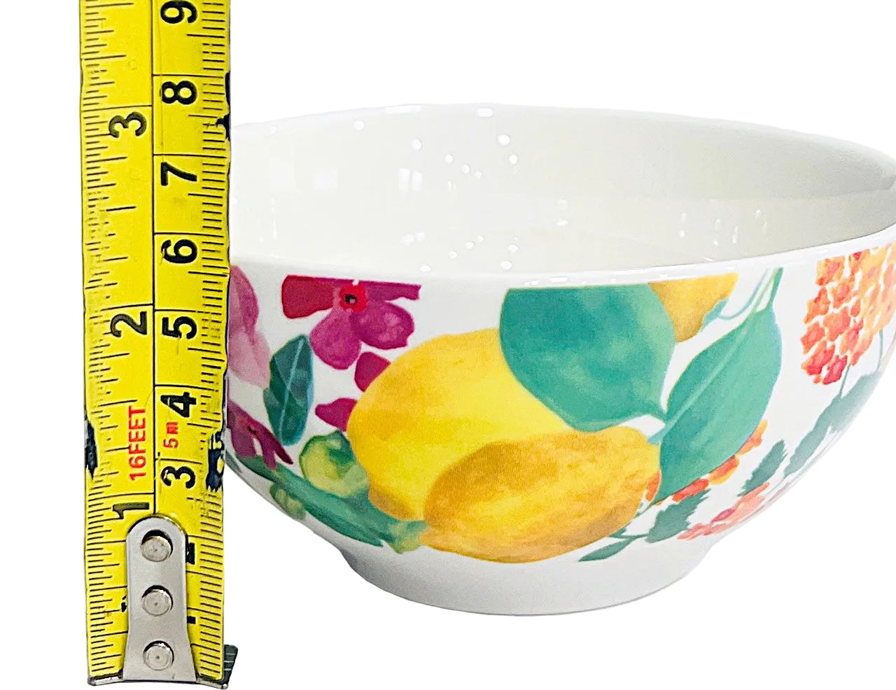 Colorful Porcelain bowl with floral and lemon design, measured by a tape measure on a white background