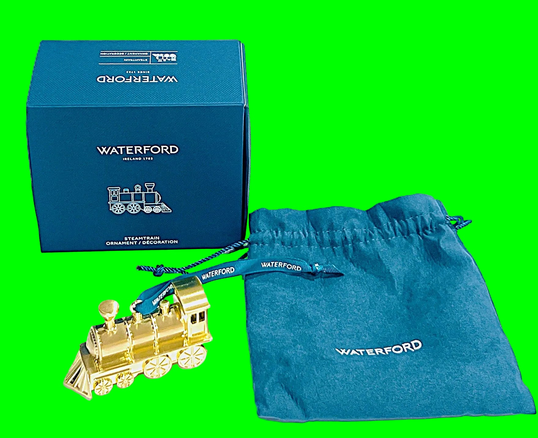 Golden train ornament with Waterford packaging on a Green background