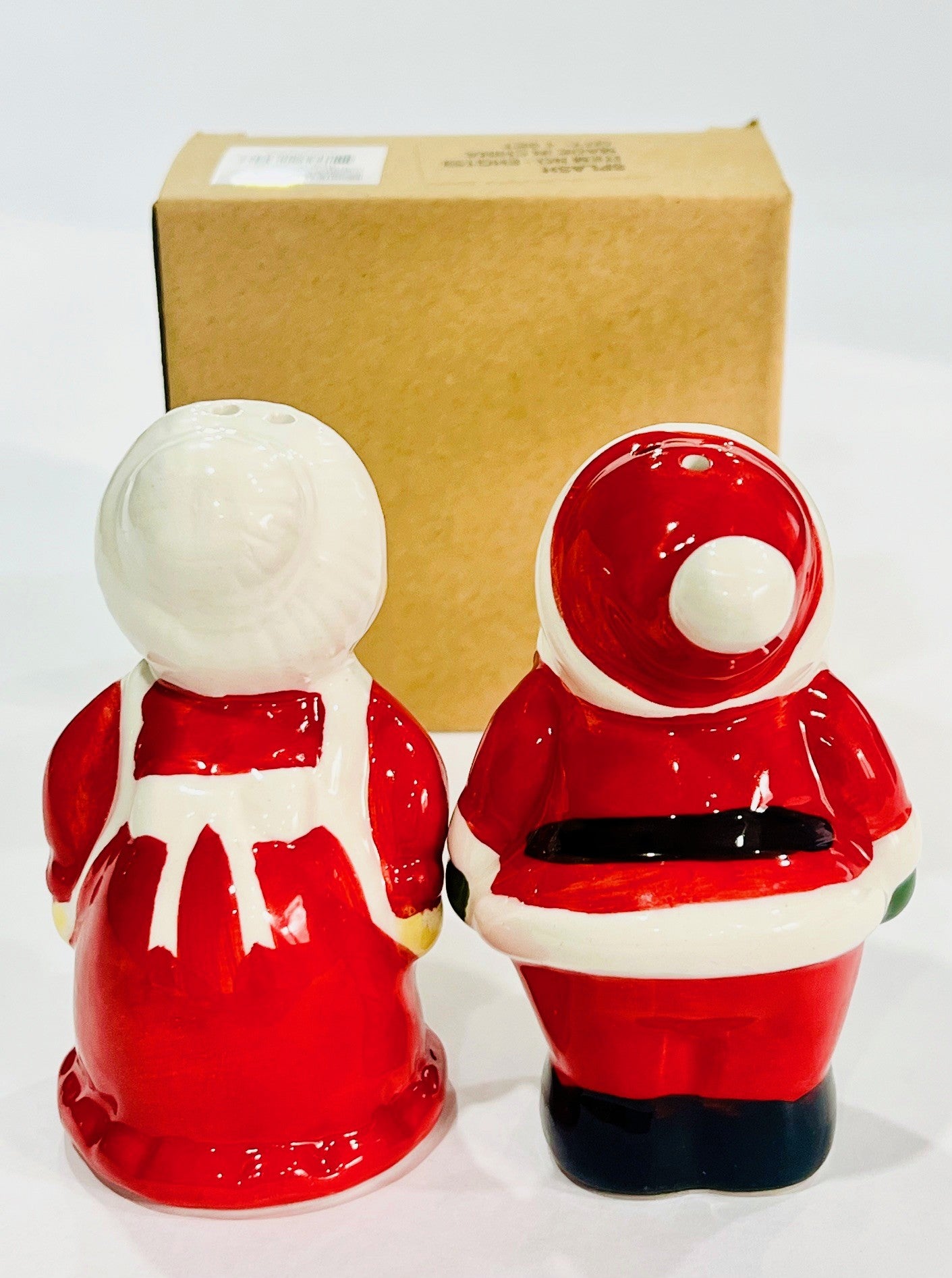 Two ceramic Santa Claus figures with a cardboard box in the background.