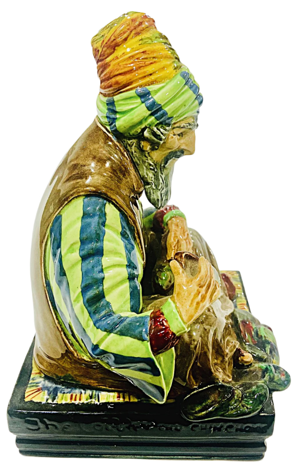 Colorful ceramic figurine of a seated figure with a patterned headscarf on a white background
