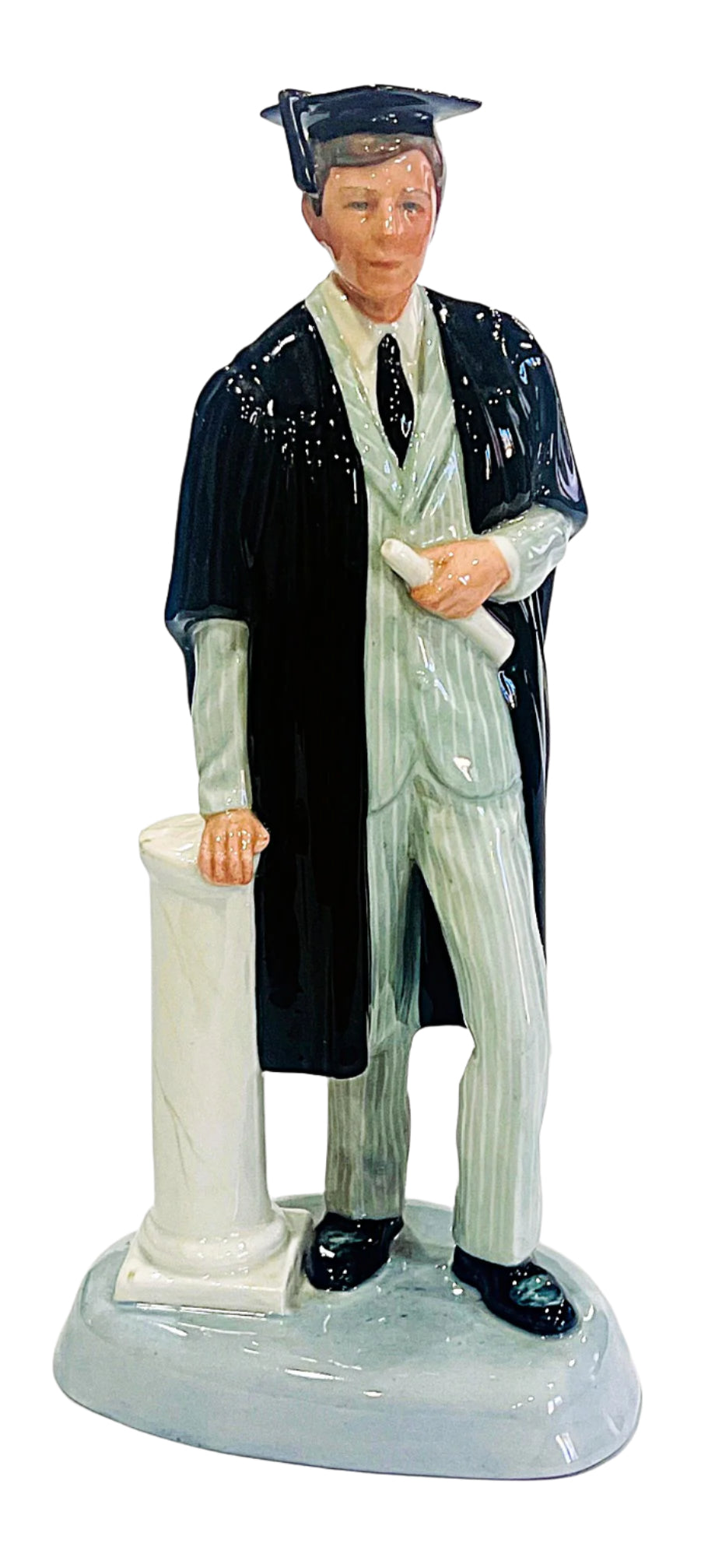 Graduation figurine of a person in cap and gown holding a diploma.