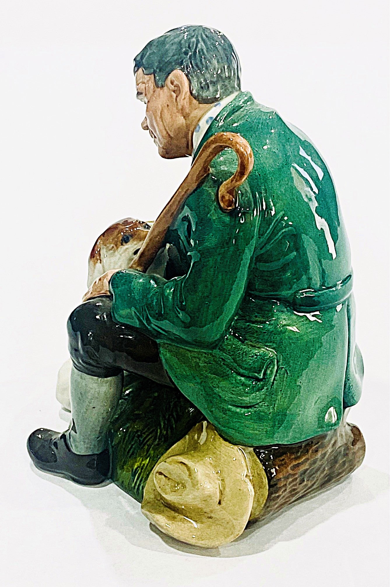 Statue of a man in a green coat sitting with a dog on a white background