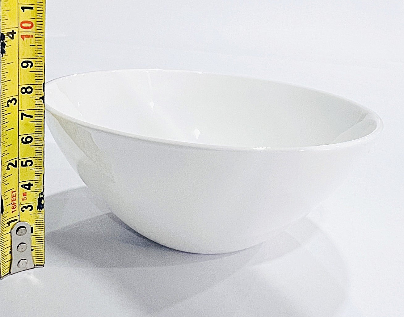 White Bone china bowl with a measuring tape on a white background