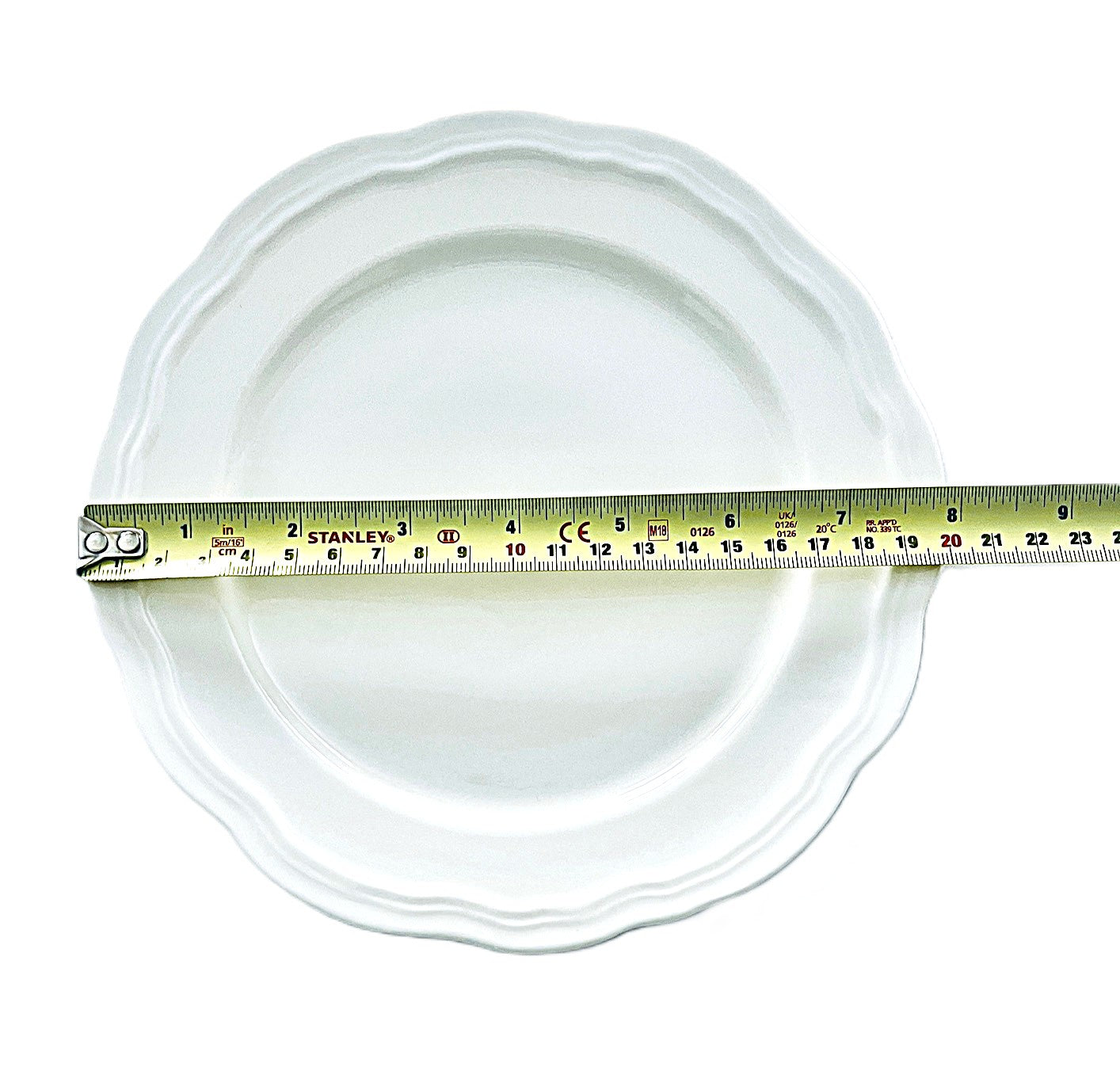 White plate with a measuring tape indicating its diameter on a white background