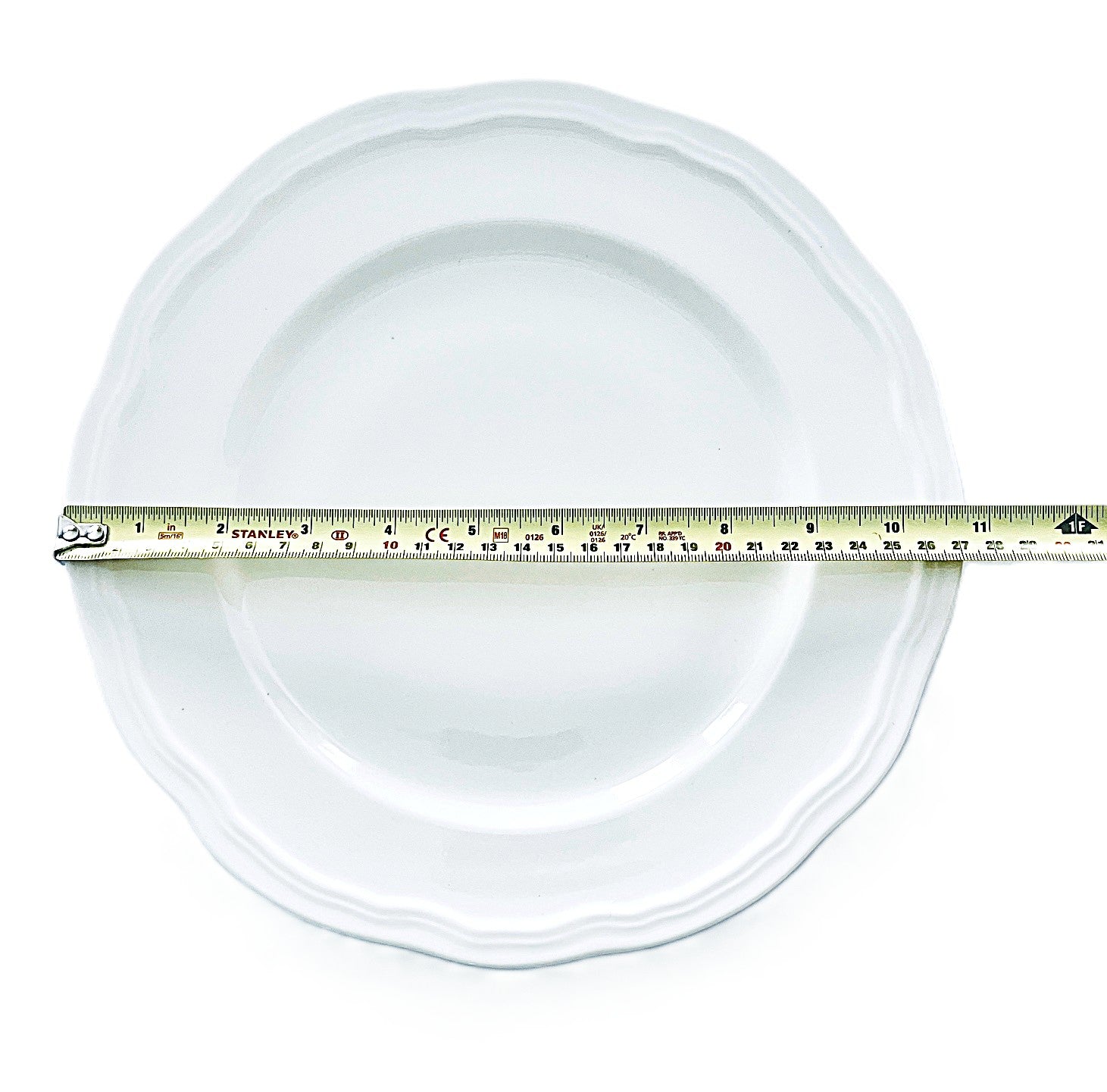 White plate with a measuring tape indicating its diameter on a white background