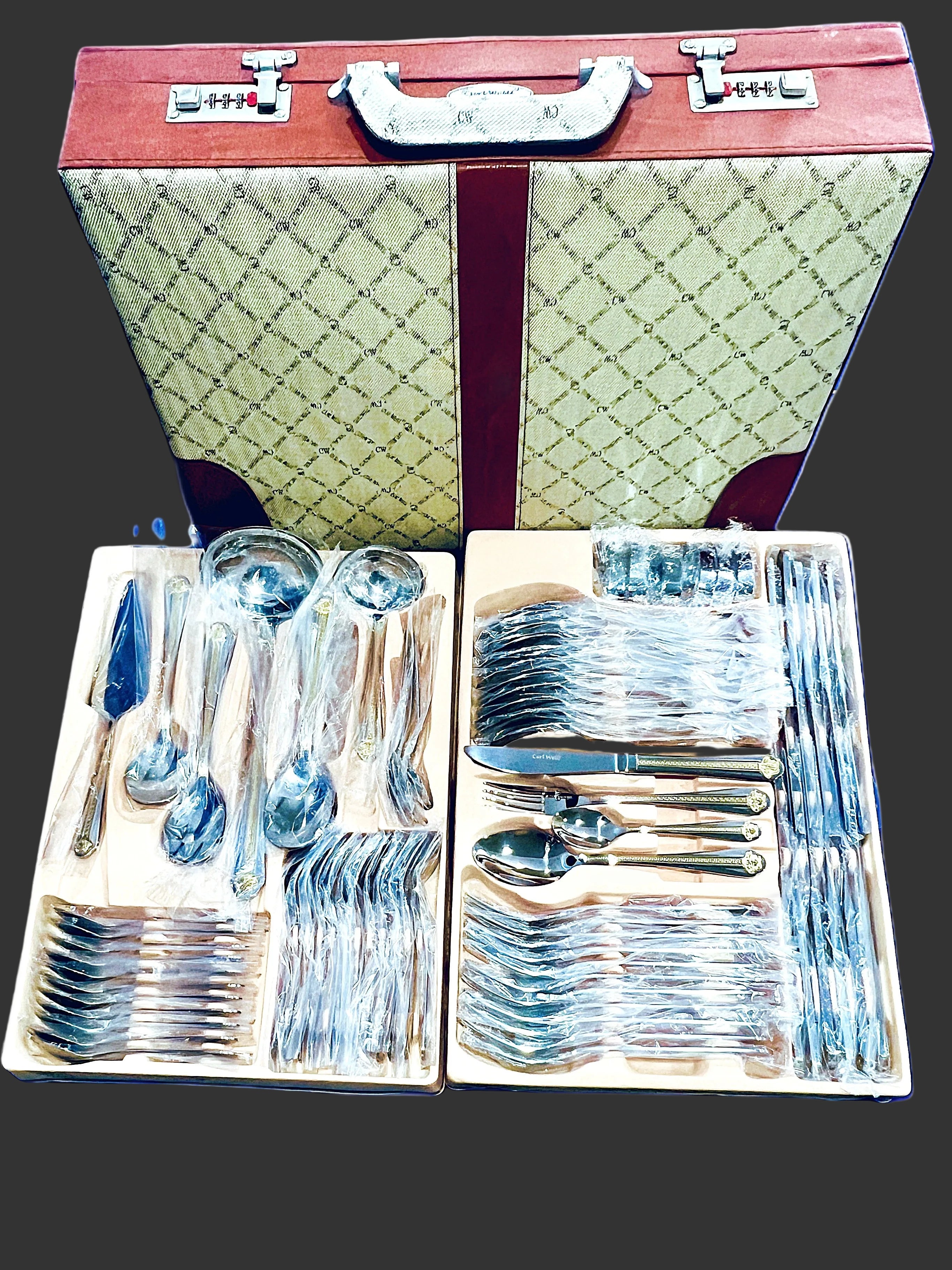 Set of silverware in a decorative case with a green and red pattern.